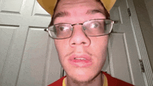 a man wearing glasses and a yellow hat looks at the camera