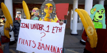 a group of people holding bananas and a sign that says idn under 1 eth that 's bananas