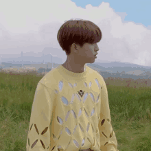 a boy wearing a yellow sweater with holes in it