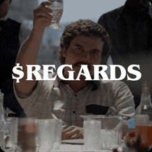 a man sitting at a table with a glass in his hand and the words $ regards behind him