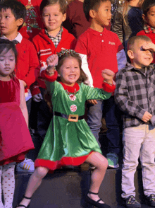 a girl in a green dress with a candy cane belt is dancing