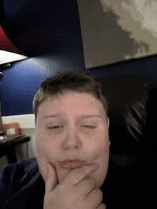 a boy is making a funny face while sitting in a chair