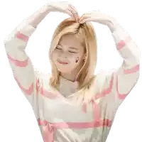 a woman wearing a pink and white striped sweater is making a heart shape with her hands