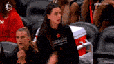 a girl wearing an all star basketball shirt is sitting in the stands at a basketball game