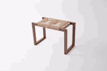 a wooden stool with a woven seat sits on a white background