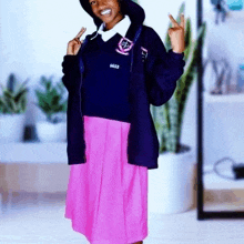 a girl wearing a pink skirt and a blue jacket is standing in a room .