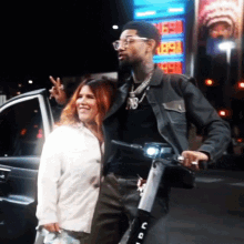 a man and a woman are posing for a picture in front of a gas station that has a sign that says 1859