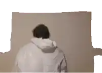 a man in a white hoodie is standing in front of a wall