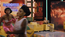 two women are dancing in front of a screen that says baddies