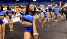 a group of cheerleaders are dancing in a gym in front of a band .