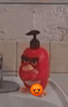 a red angry bird soap dispenser is sitting on a sink next to an orange angry face .