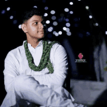 a young man is wearing a white shirt and a green scarf .