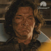 a man laying down with his eyes closed and a paramount logo in the background