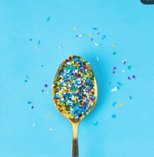 a gold spoon filled with multicolored sprinkles on a blue background