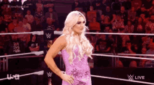 a woman in a pink dress is in a wrestling ring .