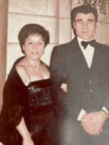 a man in a tuxedo and a woman in a dress pose for a photo