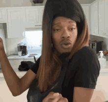 a man wearing a wig and a black shirt is standing in front of a kitchen counter