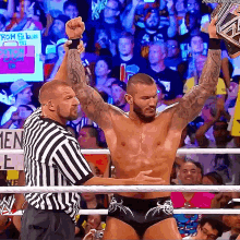 a man in a wrestling ring holds up his fist in front of a sign that says from blue to red