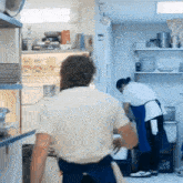 a man in a white shirt stands in front of a refrigerator with a carton of milk on the shelf