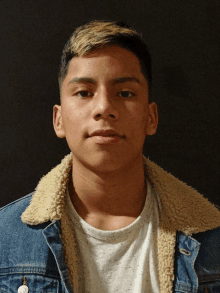 a young man wearing a denim jacket and white shirt