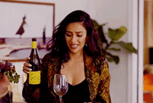 a woman is holding a bottle of wine and a glass of wine .