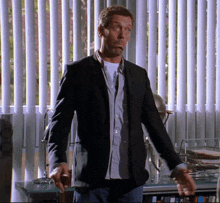 a man in a black jacket is standing in front of a window