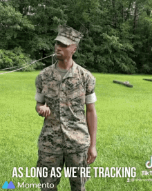 a man in a military uniform is standing in a grassy field with the words " as long as we 're tracking " below him