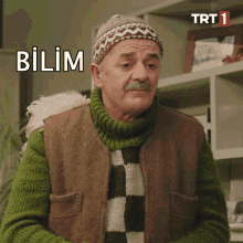 a man wearing a hat and a sweater is making a funny face and says bilim .