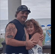 a man and a woman are posing for a picture on a beach .