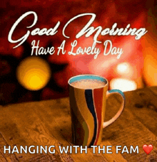 a cup of coffee on a wooden table with the words good morning have a lovely day hanging with the fam below it