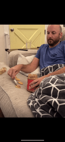 a man is sitting on a couch with a jar of peanut butter