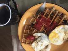 a plate of waffles eggs and a cup of tea