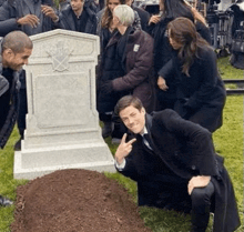 a group of people are standing around a grave in a cemetery .