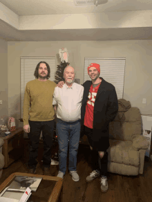 three men are posing for a picture in a living room