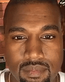 a close up of a man 's face with a beard and a white shirt .