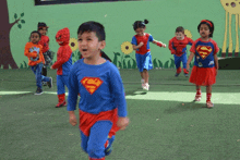 a boy in a superman costume is surrounded by other children in superhero costumes