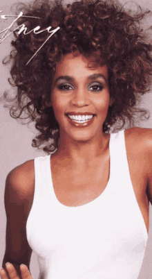 a woman with curly hair is wearing a white tank top and smiling for the camera