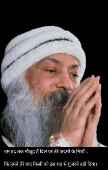 a man with a beard is wearing a white turban and praying with his hands together