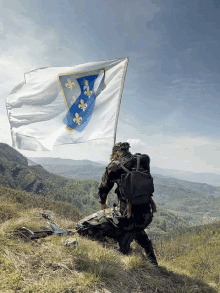 a soldier is kneeling on a hill holding a flag that says fleur de lis