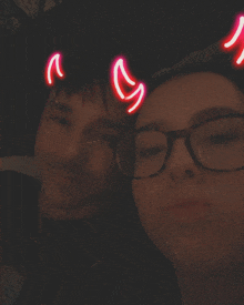 a man and a woman with neon devil horns on their heads