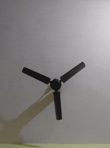 a black ceiling fan with three blades on a white ceiling