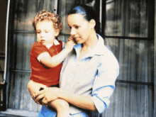 a woman in a blue shirt holds a child in her arms