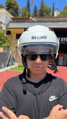 a man wearing a shiro helmet and sunglasses stands in front of a gym