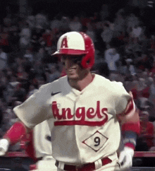 a baseball player wearing a white and red uniform with the word angels on it is standing on the field .