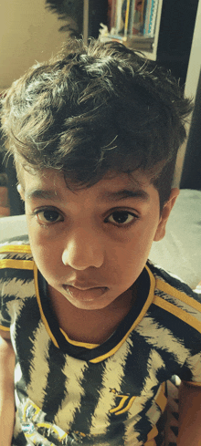 a young boy wearing a black and yellow striped shirt with the word juventus on the front