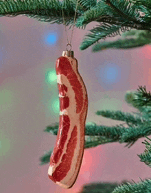 a bacon ornament hangs on a christmas tree