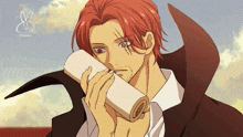 a man with red hair is holding a piece of paper in his mouth