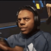 a man wearing headphones and a blue hoodie looks at the camera