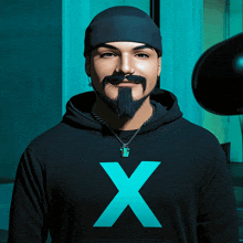 a man with a beard is wearing a black hoodie with a blue x on it