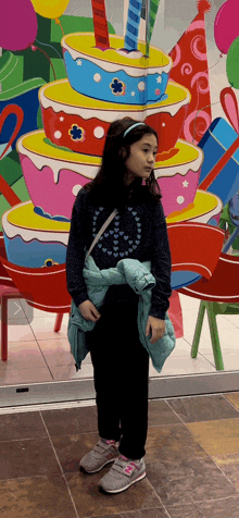 a girl standing in front of a birthday cake display